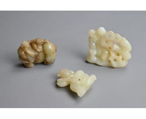 THREE CHINESE CELADON JADE CARVINGS. To include a pale celadon jade figure of a boy holding a lotus spray; A celadon jade car