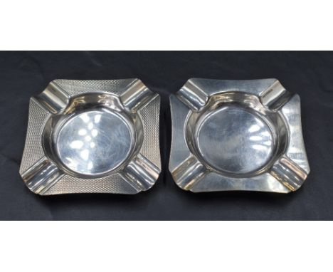 A near pair of Queen Elizabeth II silver ashtrays, of canted square form with moulded rests to each corner, one with engine-t