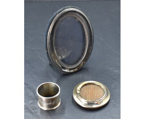 An modern oval  silver photograph with black velvet easel back, a small circular silver photo frame with wooden easel back an