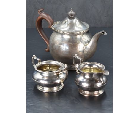 A matched George V silver three piece teaset, comprising teapot, sugar and cream, the teapot of globular form with hinged fin