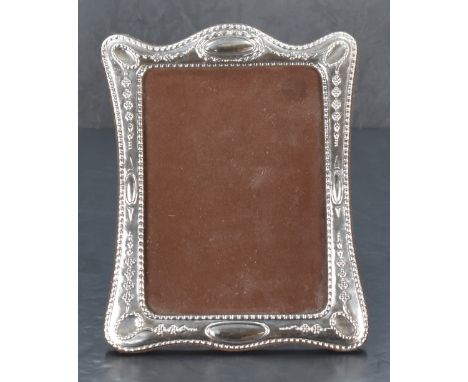A modern white metal-mounted photograph frame, of traditional design with embossed decoration and lightly planished surface, 