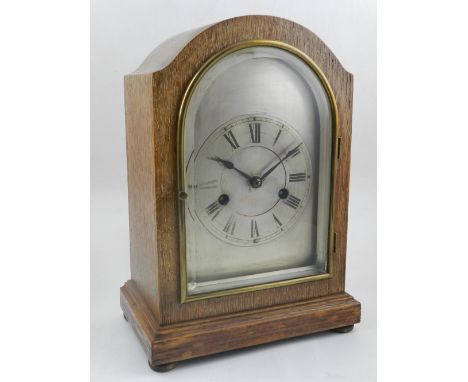 An early 20th century limed oak cased mantle clock, the silvered dial with a twin train movment striking a gong, H. 129cm.