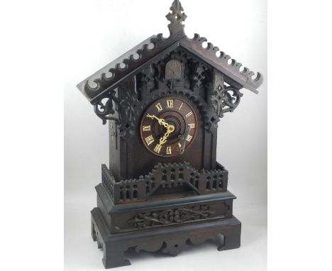 An early 20th century Black Forest cuckoo clock, the ornately carved case with scrolling foliage, the wooden dial with Roman 