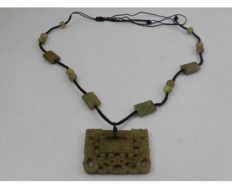 A jade pendant, carved of rectangular form suspended form a cord,  