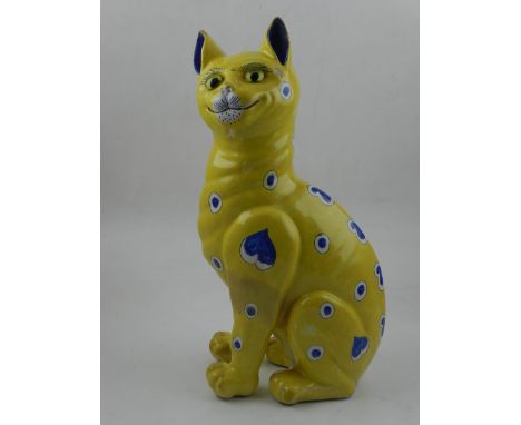 A Galle style ceramic model of a cat, decorated with blue and white hearts and circles on a yellow ground. H: 33cm