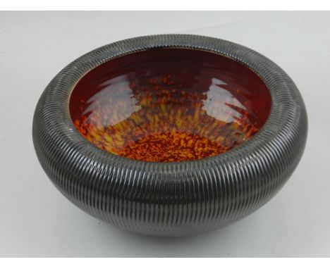 A Poole studio ceramic bowl, the exterior decorated with impressed reeded design, the interior with orange and red drip glaze