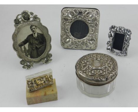 A silver mounted cold creme jar, three white metal picture frames and another item.