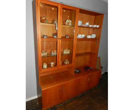 A teak display cabinet, with a pair of glazed panel doors, the lower section with four panel doors, on a plinth base. 