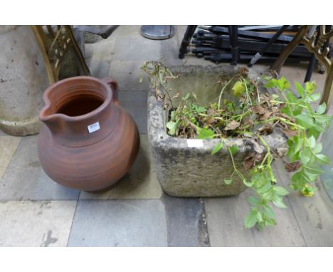 A concrete garden planter and terracotta jug