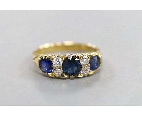 A late Victorian 18ct gold, three stone sapphire, and four stone diamond set half hoop ring, with carved setting, size O, gro