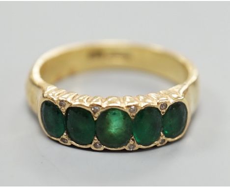 A modern 18ct gold and graduated five stone emerald set half hoop ring, with diamond chip spacers, size Q/R, gross weight 7.5