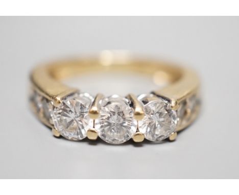 A 14k yellow metal and three stone diamond ring, with four stone diamond set shoulders, size K, gross weight 4.3 grams, the t