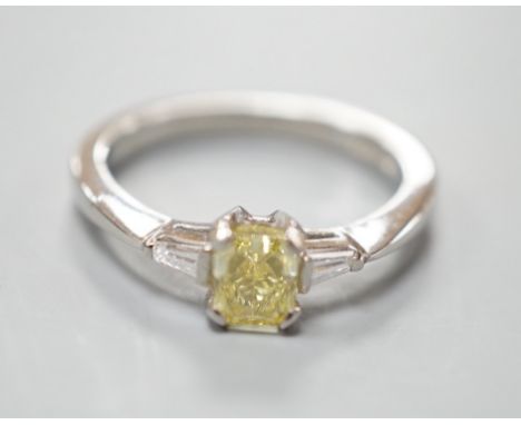 A modern platinum and single stone fancy yellow diamond set ring, with trapeze cut diamond set shoulders, size N, gross weigh