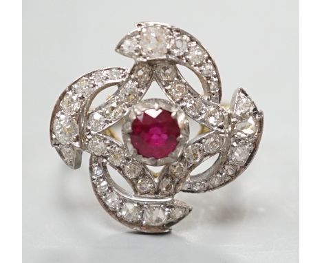 A yellow metal, ruby and diamond cluster set dress ring, in a pierced scroll setting, size O, gross weight 6 grams.