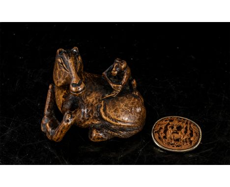 Japanese Okimono in the form of a seated horse with a monkey on its back, together with carved netsuke brooch.