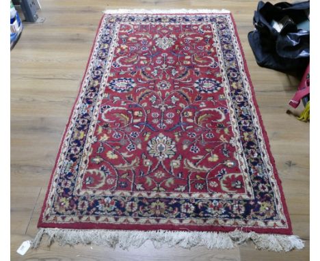 Floral patterned and fringed red rug, 157 cm x 92 cm