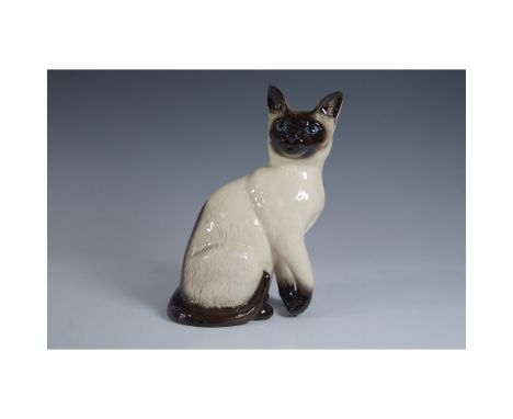 A Royal Doulton seated Siamese cat figurine, model D127. This finely crafted ceramic sculpture features a lifelike depiction 