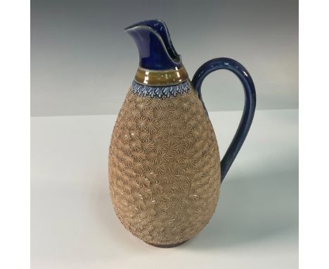 This Doulton Lambeth stoneware pitcher features a textured body with intricate applied decorations, including a floral-inspir