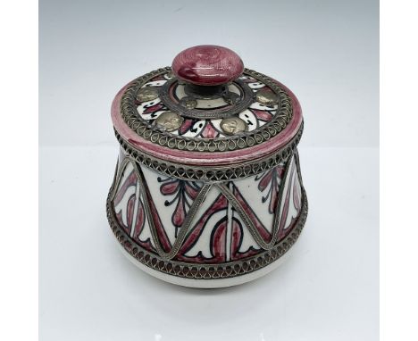 This Moroccan ceramic lidded jar features a hand-painted design in vibrant red, white, and black hues, accented with intricat