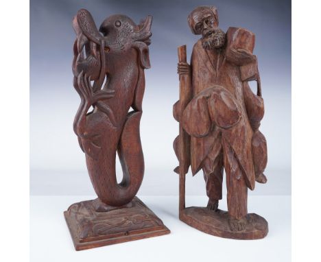A pair of finely hand-carved wooden sculptures featuring a man carrying bags and holding a walking stick, alongside a mythica