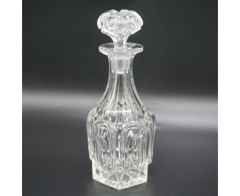 This elegant cut glass decanter features a hexagonal base adorned with intricate cut patterns, leading up to a beautifully de