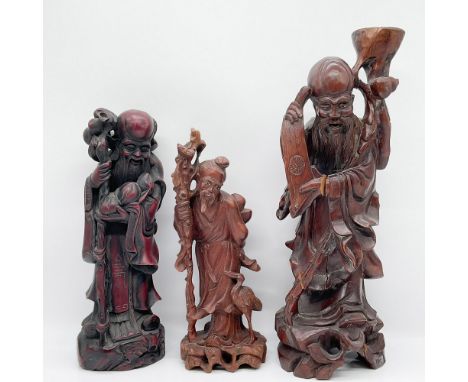 A set of three intricately hand-carved wooden figurines depicting wise men or sages, crafted in a traditional Chinese style. 