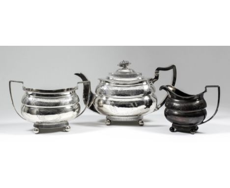 A George III silver rectangular three-piece tea service, with bead mounts, the bulbous bodies engraved with leaf and floral o