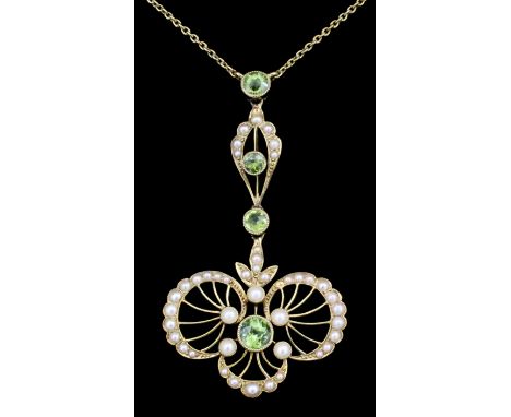 An Edwardian 15ct gold peridot and seed pearl set pendant, the scrolling face set with four peridots within borders set with 