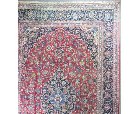 A large Kashan carpet woven in colours, central leaf and floral filled medallion and conforming spandrels, field filled with 