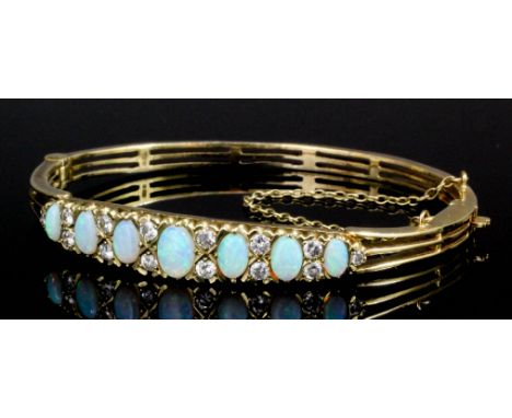 A modern 9ct gold opal and diamond set stiff bangle in the Victorian style, the face set with seven oval opal cabochons rangi