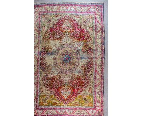 A Lavar Kirman carpet woven in colours, the bold floral filled central medallion in conforming spandrels, floral filled field