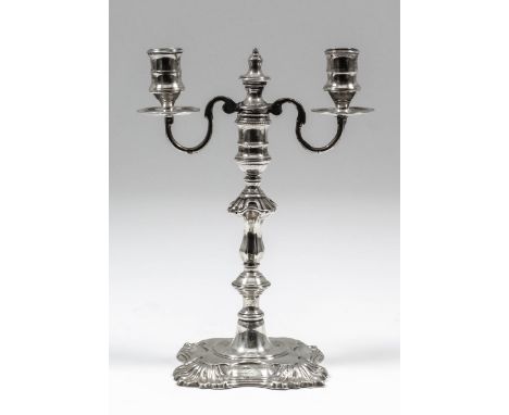 A George III cast silver taper stick with knopped and baluster shape stem, the square shaped base with shell capped corners, 