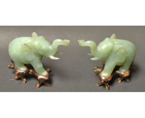 A pair of Chinese jade elephants, on hardwood stands
