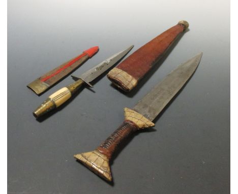 A 20th century North African dagger, the blade with etched geometric decoration, within a leather scabbard, together with ano