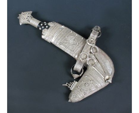 An Omani Jambiya, the curved steel blade with raised medial ridge, with silver mounted ebonised waisted grip, the leather sca