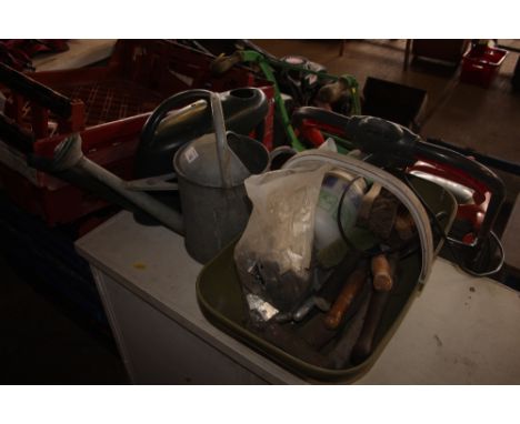 A plastic trug of various hand tools; a galvanised watering can; and a plastic watering can 