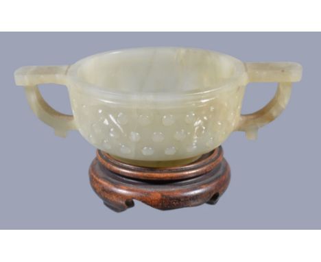  A Chinese small celadon jade two-handled bowl,   Qing Dynasty,  the exterior carved with three rows of raised circular bands