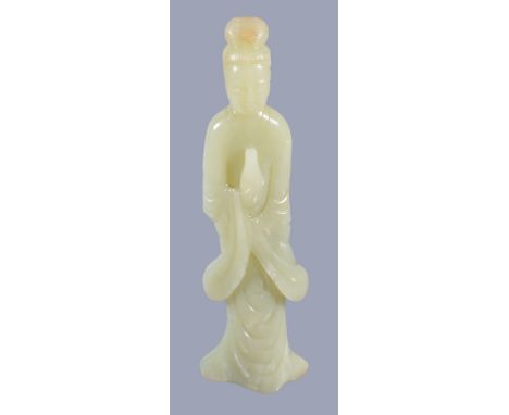  A large Chinese celadon jade carving of a lady  , with white and russet inclusions, standing holding a vase and wearing flow