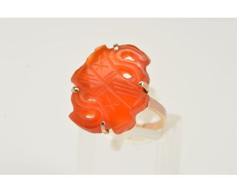 A CARVED CARNELIAN RING, the carved and pierced carnelian panel within a four claw setting to the plain band, stamped 14k, ri
