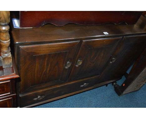 AN ERCOL DARK OAK SIDEBOARD with one large cupboard door to one side and two doors over one long drawer standing on tapered l