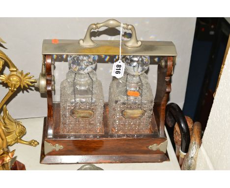 A LATE VICTORIAN SILVER PLATED AND OAK TANTALUS, unbranded, fitted with two cut glass square decanters with spherical stopper