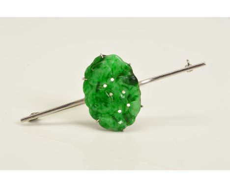 A JADE BAR BROOCH, designed as a central oval jade panel carved with fruit to the plain bar brooch, stamped 9ct, length 57mm,