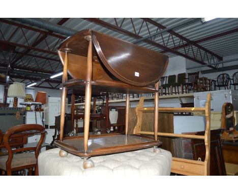 A DARK ERCOL OVAL DROP LEAF TEA TROLLEY on orbit caster