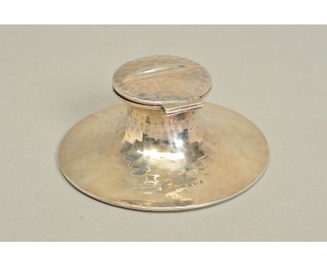 AN EDWARDIAN SILVER CAPSTAN INKWELL, pen rest to hinged cover, planished surface, ceramic liner, diameter 14cm