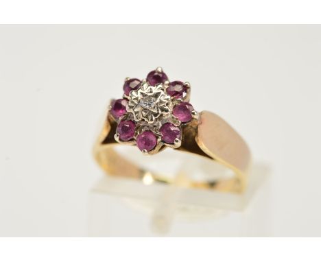 A 9CT GOLD RUBY AND DIAMOND CLUSTER RING, designed as a central single cut diamond within a star setting to the circular cut 