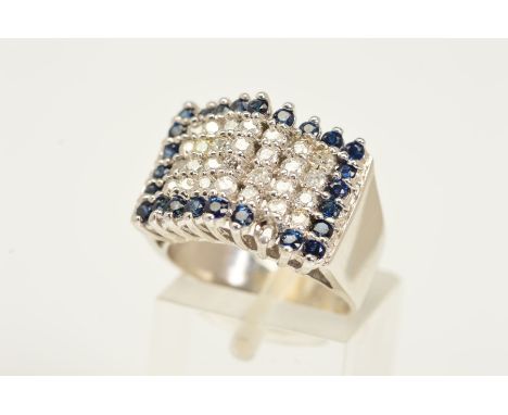 A DIAMOND AND SAPPHIRE RING, a tiered rectangular panel set with four rows of brilliant cut diamonds with circular sapphire s