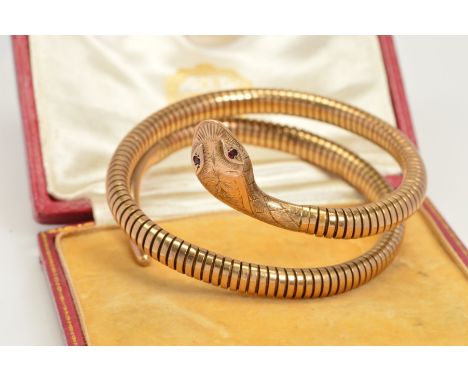 A COILED SNAKE BANGLE, of sprung design in a double coil, with red gem eyes, engraved decoration to the head and tail, head w