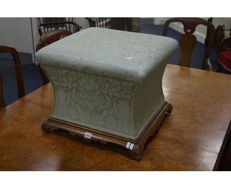 A VICTORIAN UPHOLSTERED FOOTSTOOL over concave sides on a walnut base and ceramic casters, 50cm squared x height 42cm