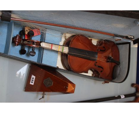 A cased violin and bow, together with some sheet music and a metronome 'Mablzel Paquet Fabrication (2)