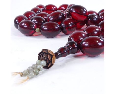 A large string of simulated amber beads, with intermittent jade beads, and jade and carved wood tassel, bead length 35mm 